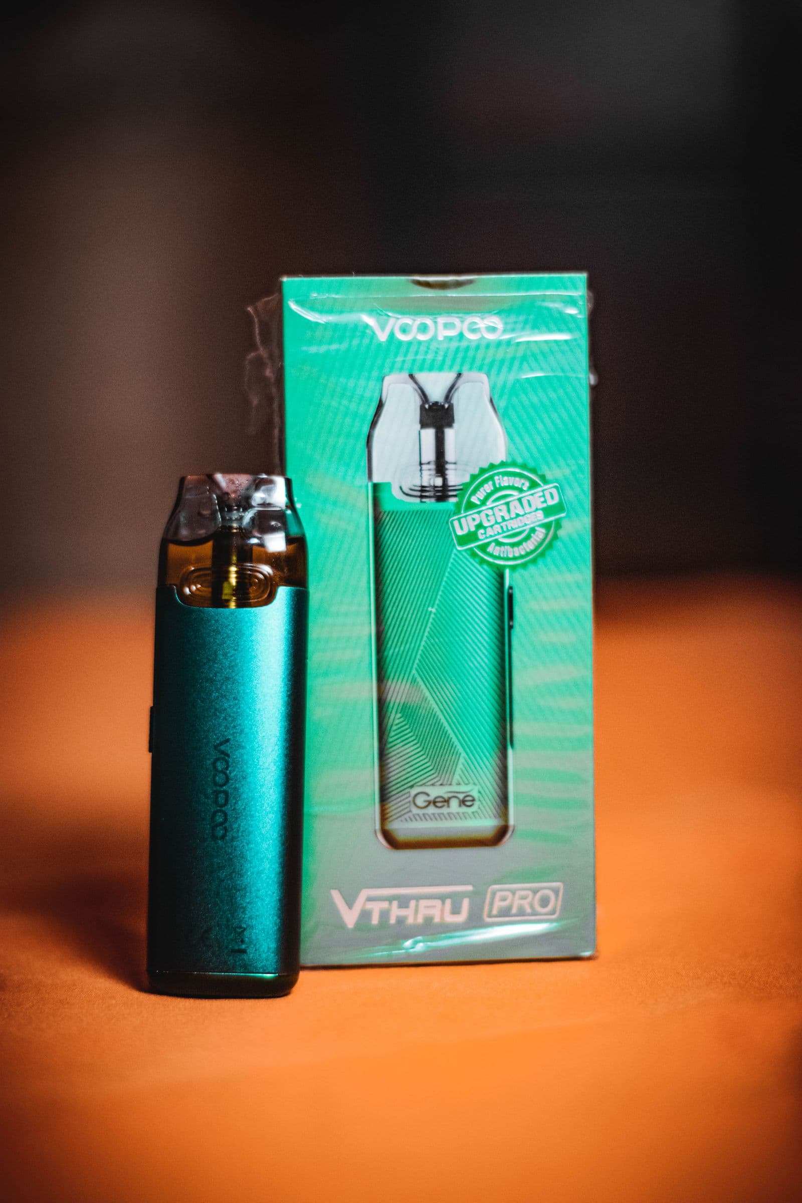 Teal pod device beside its retail box