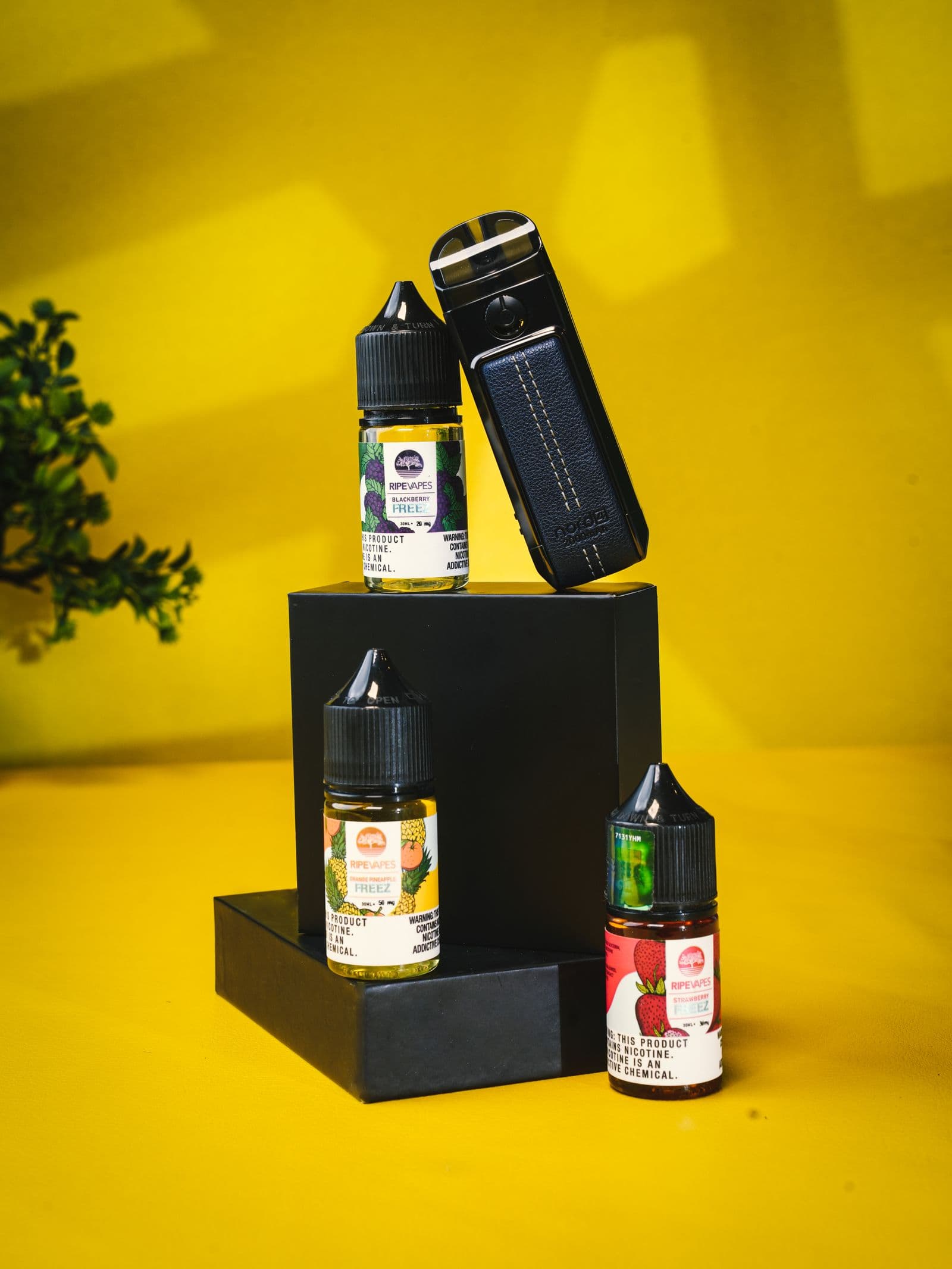 E-liquid bottles and a pod device displayed on a yellow backdrop